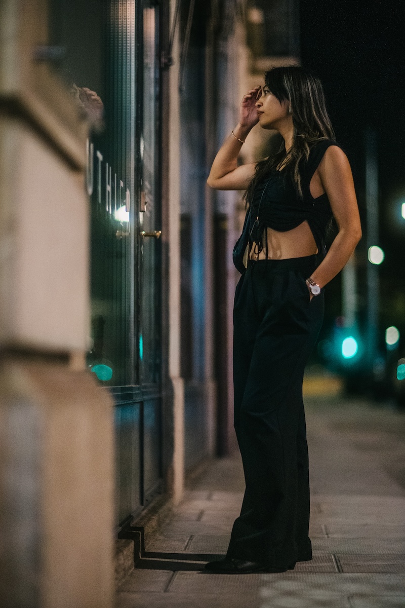 Medium night portrait of a woman looking sideways towards a illuminated shop window with soft background bokeh