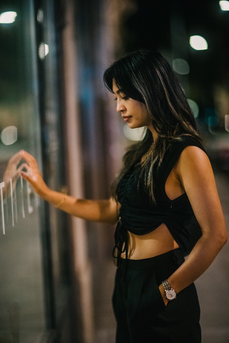Intimate close-up portrait of a woman touching the glass of a shop window in Geneva at night