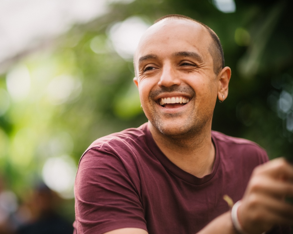 Candid portrait of a smiling guest in natural light at an outdoor private event in Switzerland, captured in a cinematic documentary style.