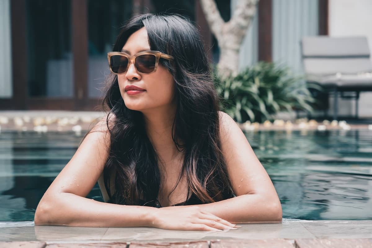 Cinematic portrait of a woman wearing sunglasses in a pool, captured with a narrative and film-inspired aesthetic