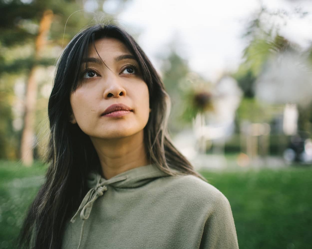 Close up cinematic portrait of a woman looking thoughtfully upward in the natural light of Parc André-Chavanne in the neighbourhood of Petit-Saconnex in Geneva.