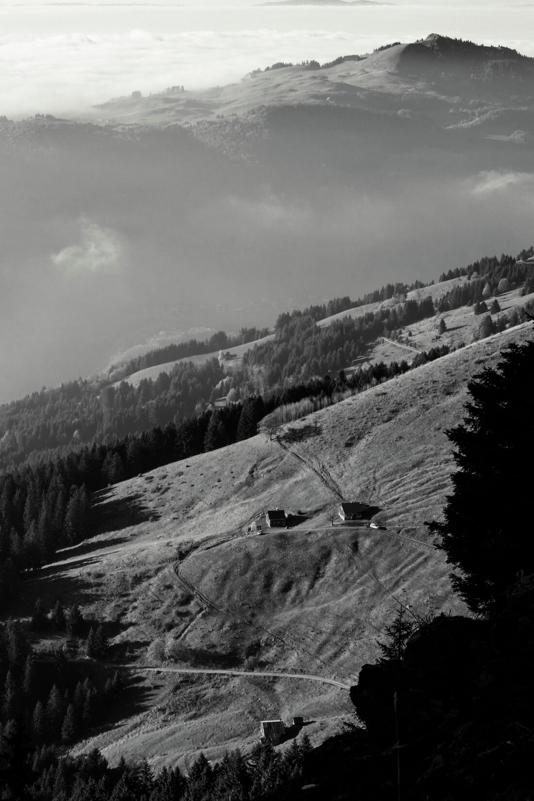 Fine art black and white photograph of chalets nestled in peaceful mountain pastures