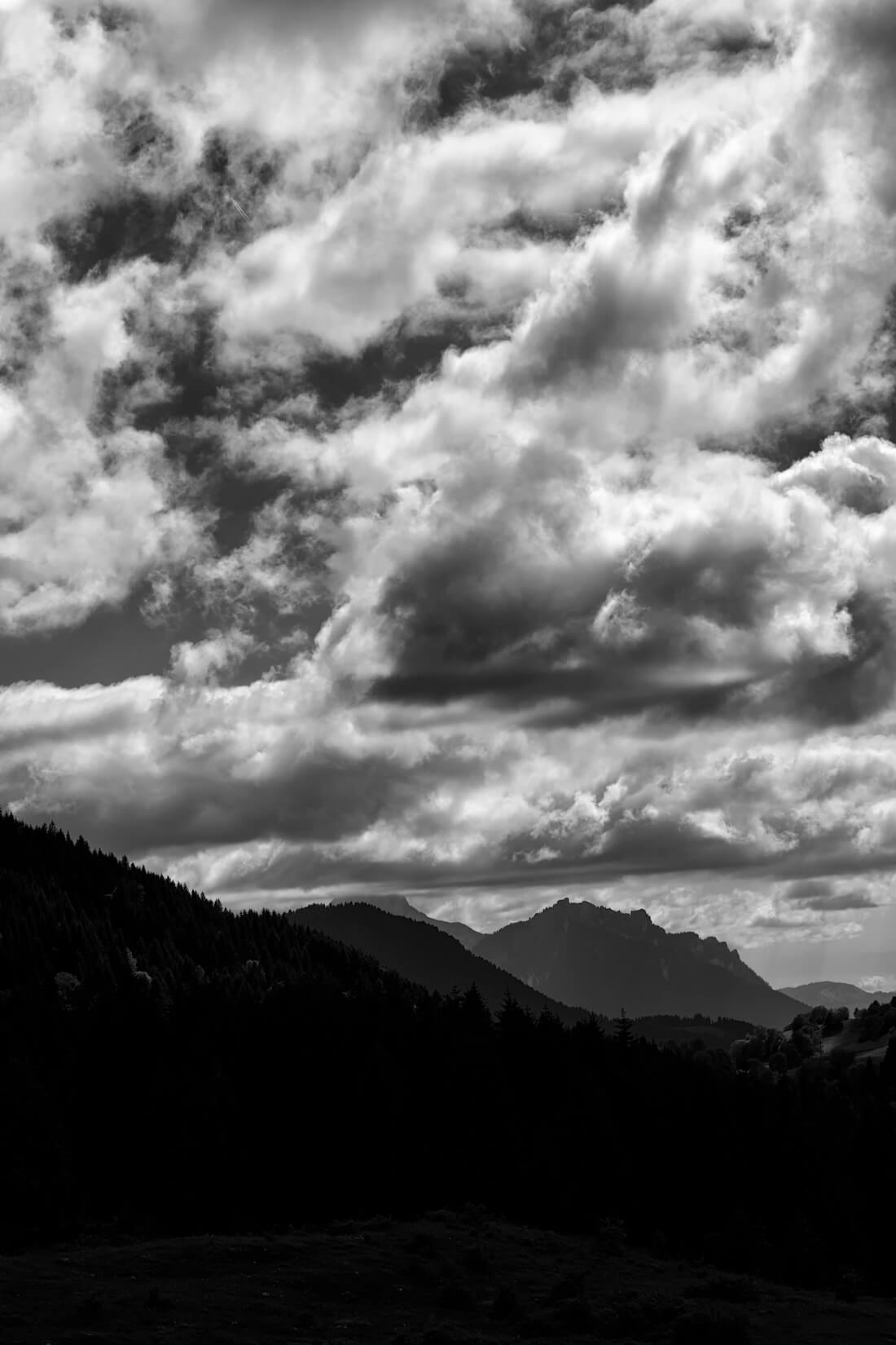Fine art black and white photograph of mountains enveloped in clouds, creating a dramatic cloudscape