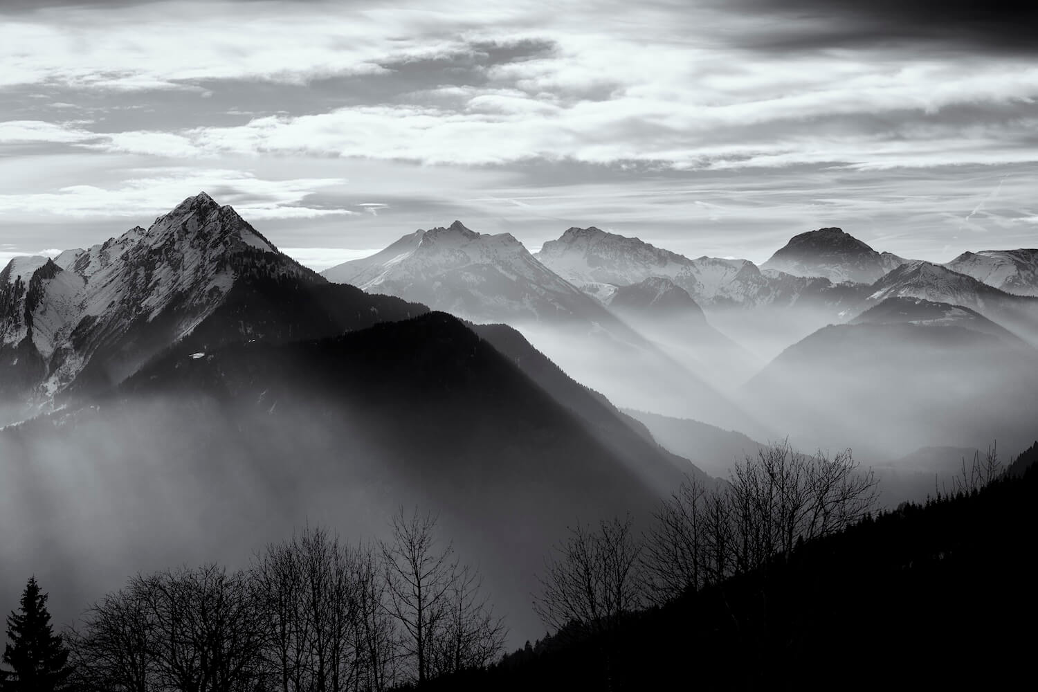 Fine art black and white photograph of mountains with ethereal mist drifting through the valley