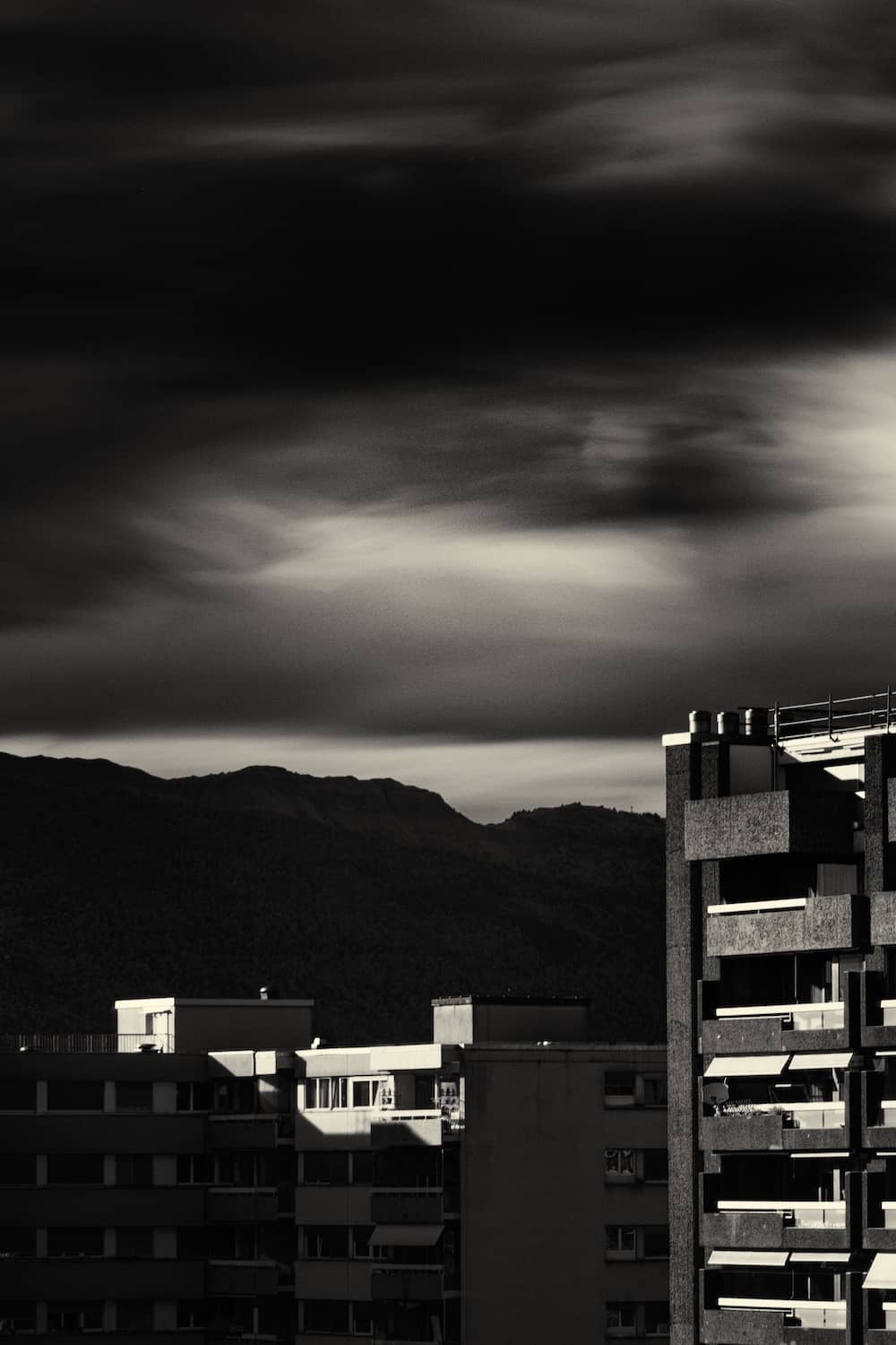 Black and white infrared fine art landscape of the Jura mountains framed by buildings in Geneva