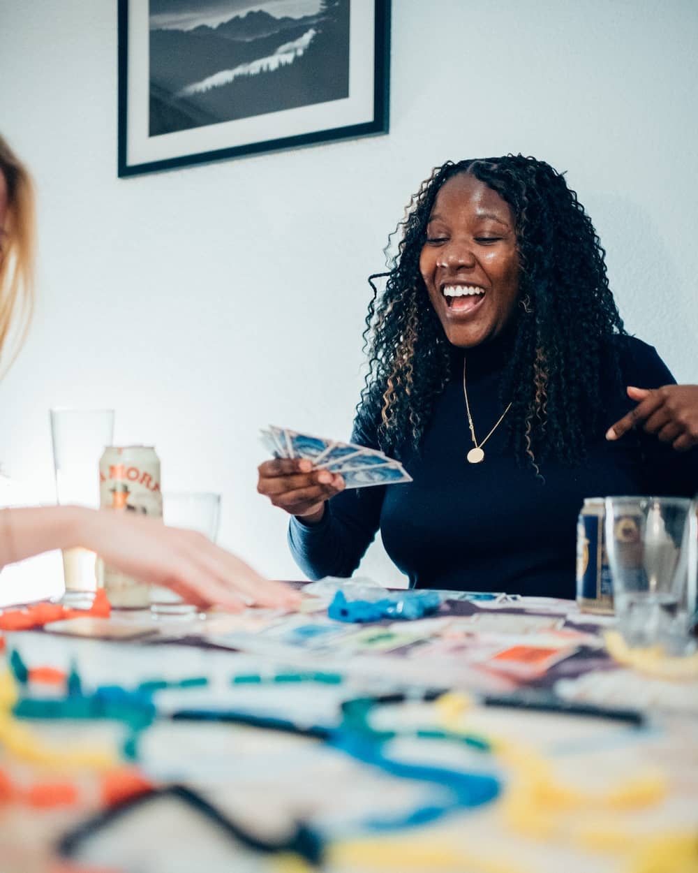Lifestyle photography of a woman laughing genuinely during a board game night with friends in Geneva. Cinematic style with shallow depth of field, captured in natural light by Pierre-Alexandre Photography.