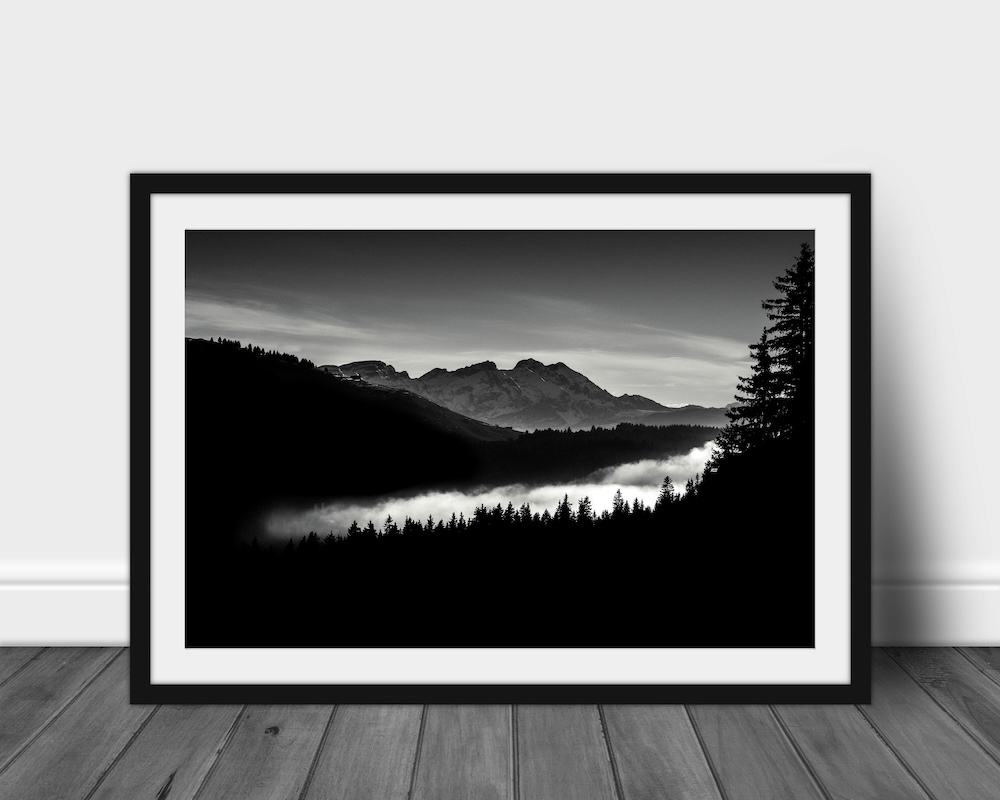 Black and white landscape of a sea of clouds flowing into a mountain valley, creating an ethereal atmosphere