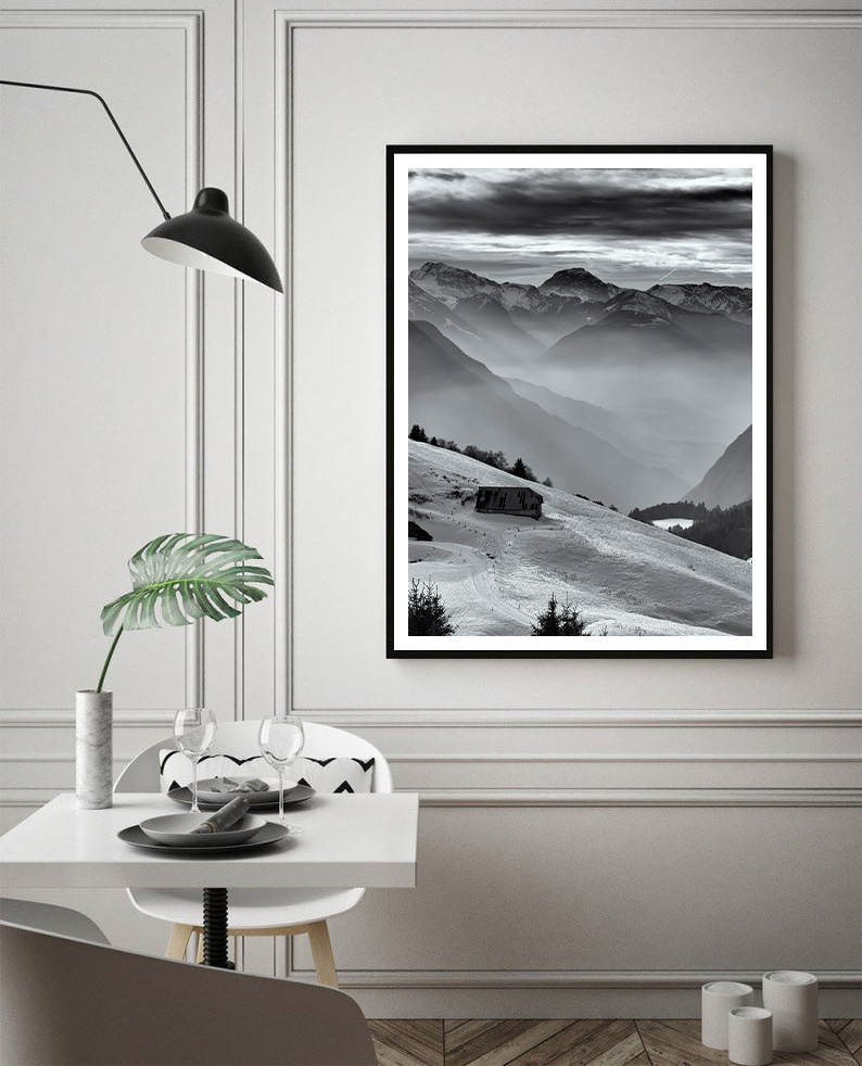 Fine art black and white photograph of a snowy chalet surrounded by a magical mountain landscape